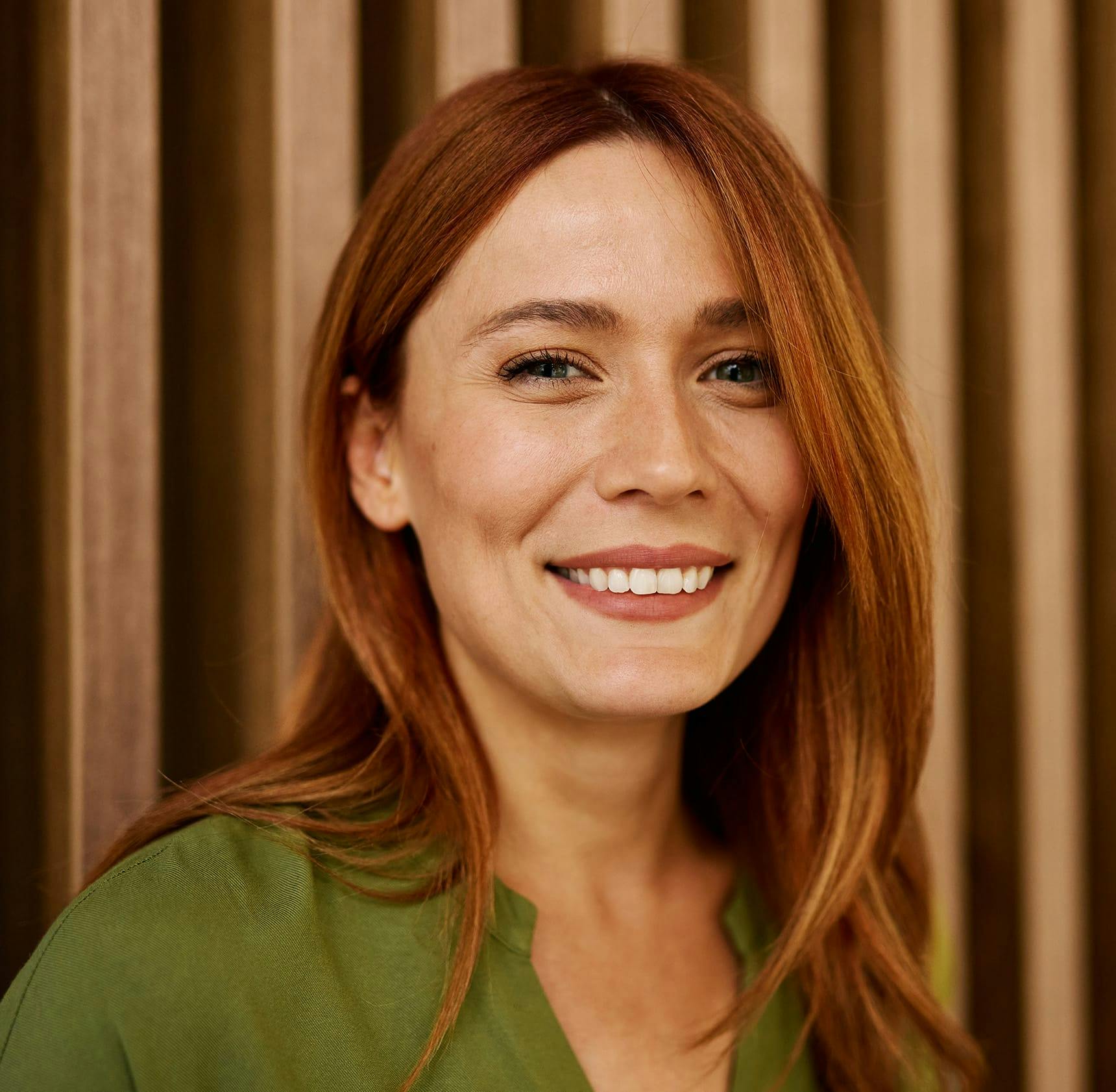 red head woman smiling and wearing a green shirt