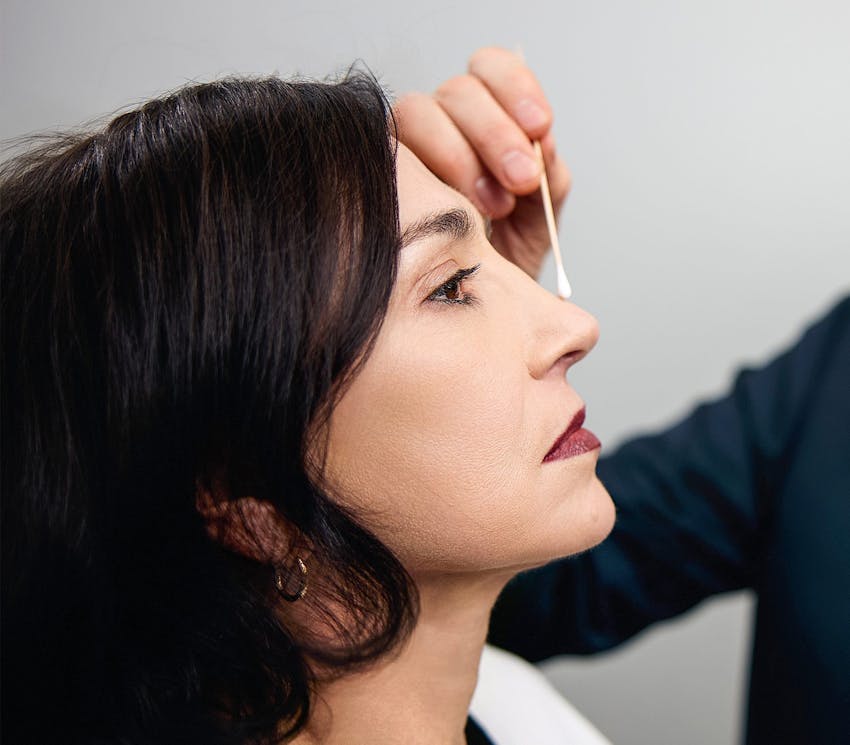 side profile of woman getting the bridge of her nose checked by doctor