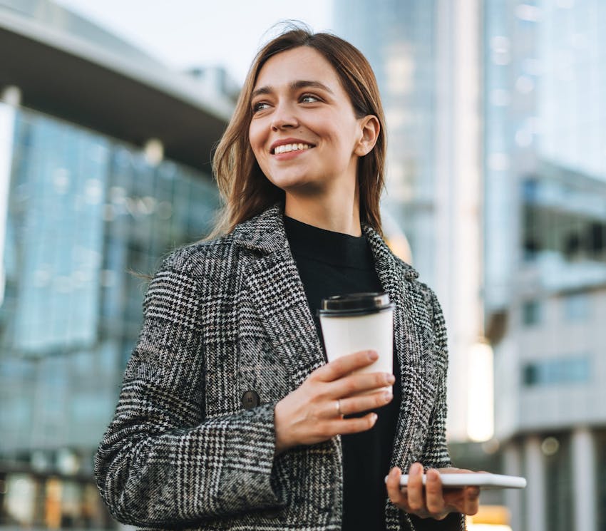 woman walking in the city holding a cup of coffee