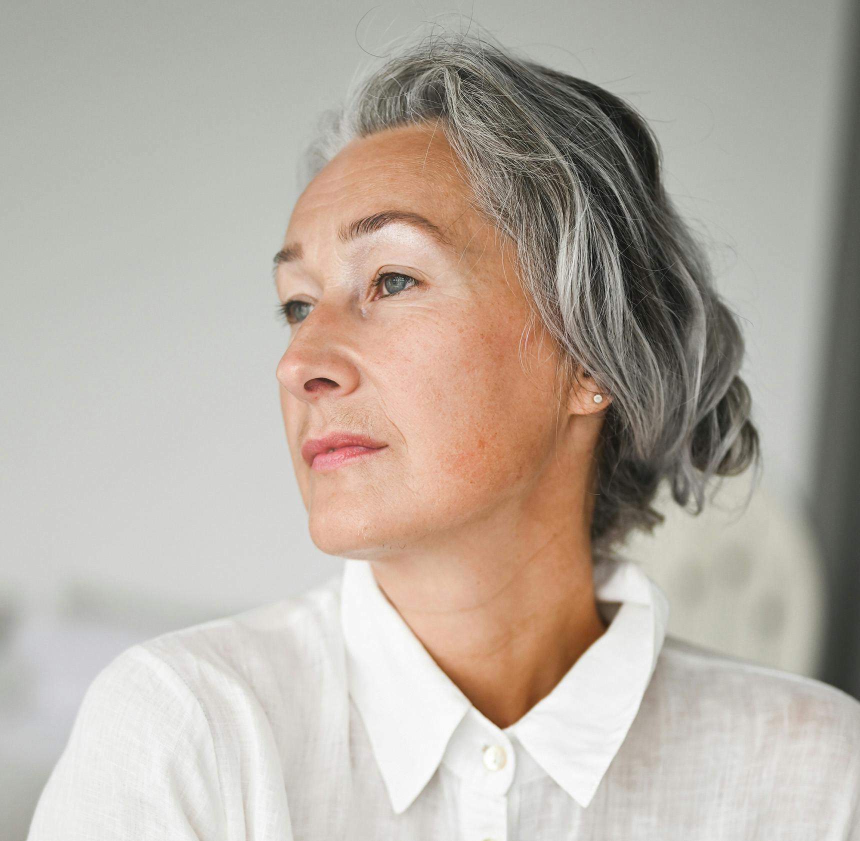 woman with grey hair wearing a white shirt
