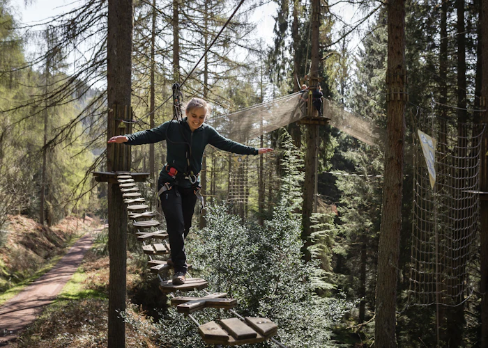 Person steps over a high ropes crossing.