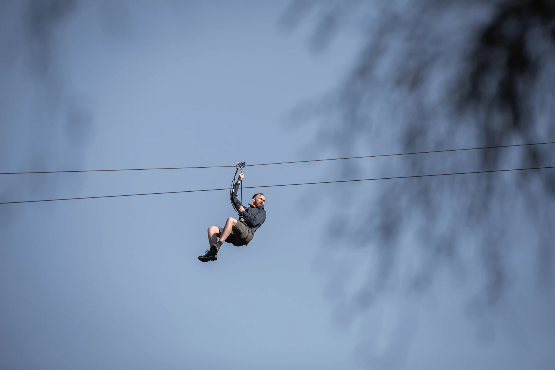 Person on a zip wire in front of a clear sky.