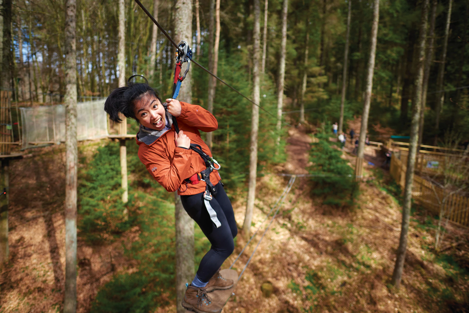 Person going along a zip wire while grinning.