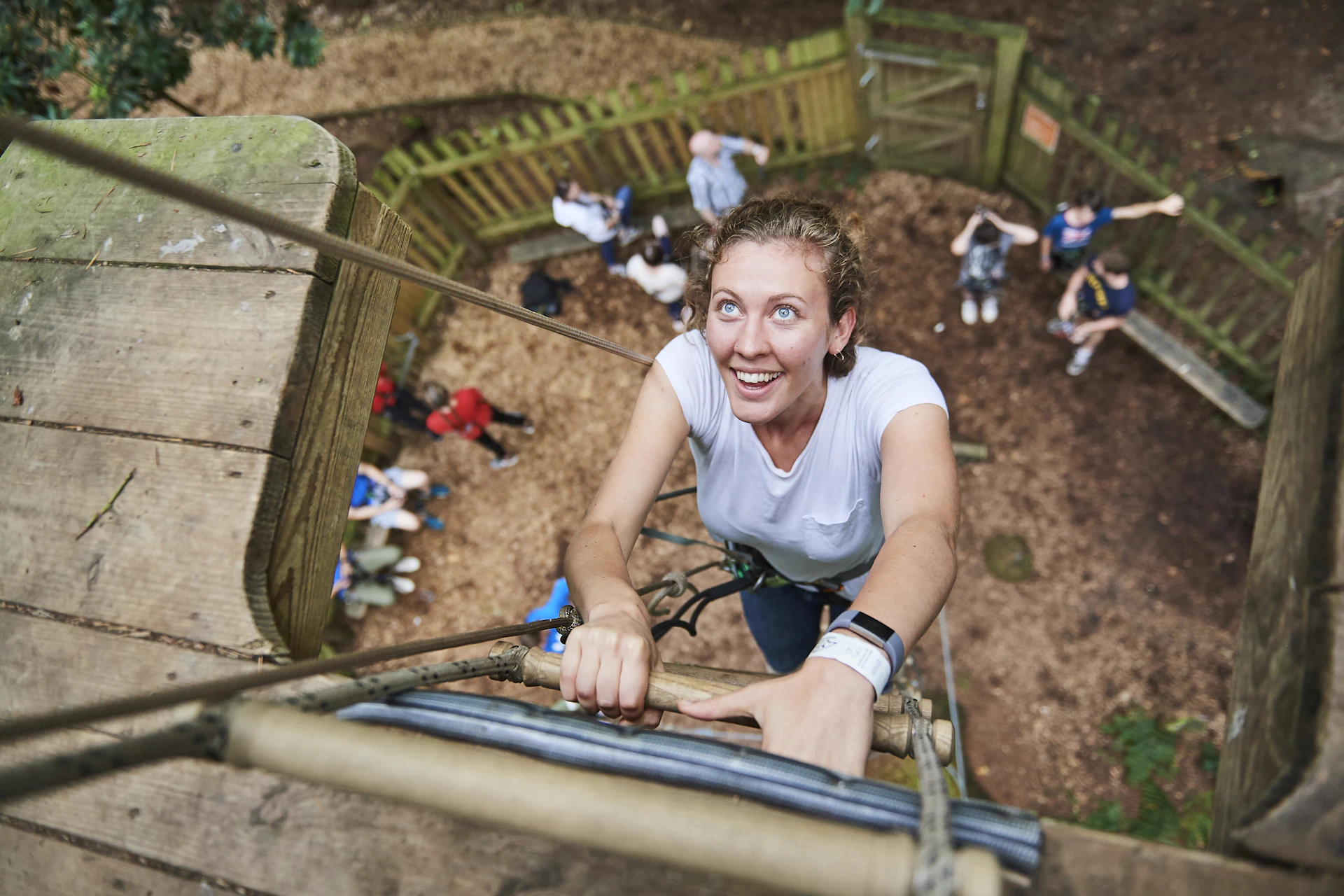 Person climbs up a ladder towards the camera while smiling.