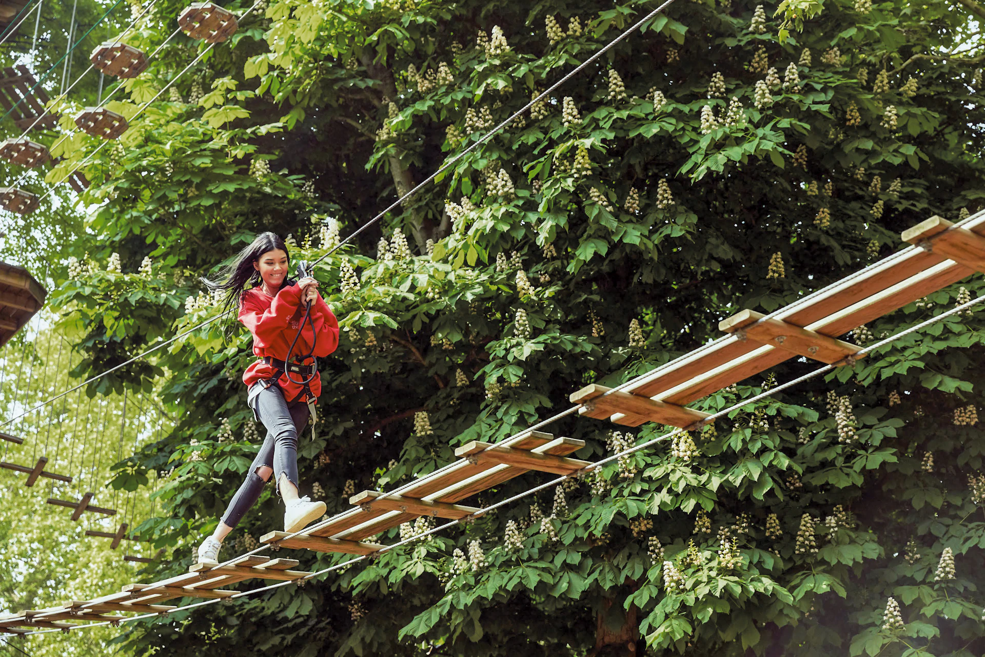 Person stepping across a wooden high ropes crossing and smiling.