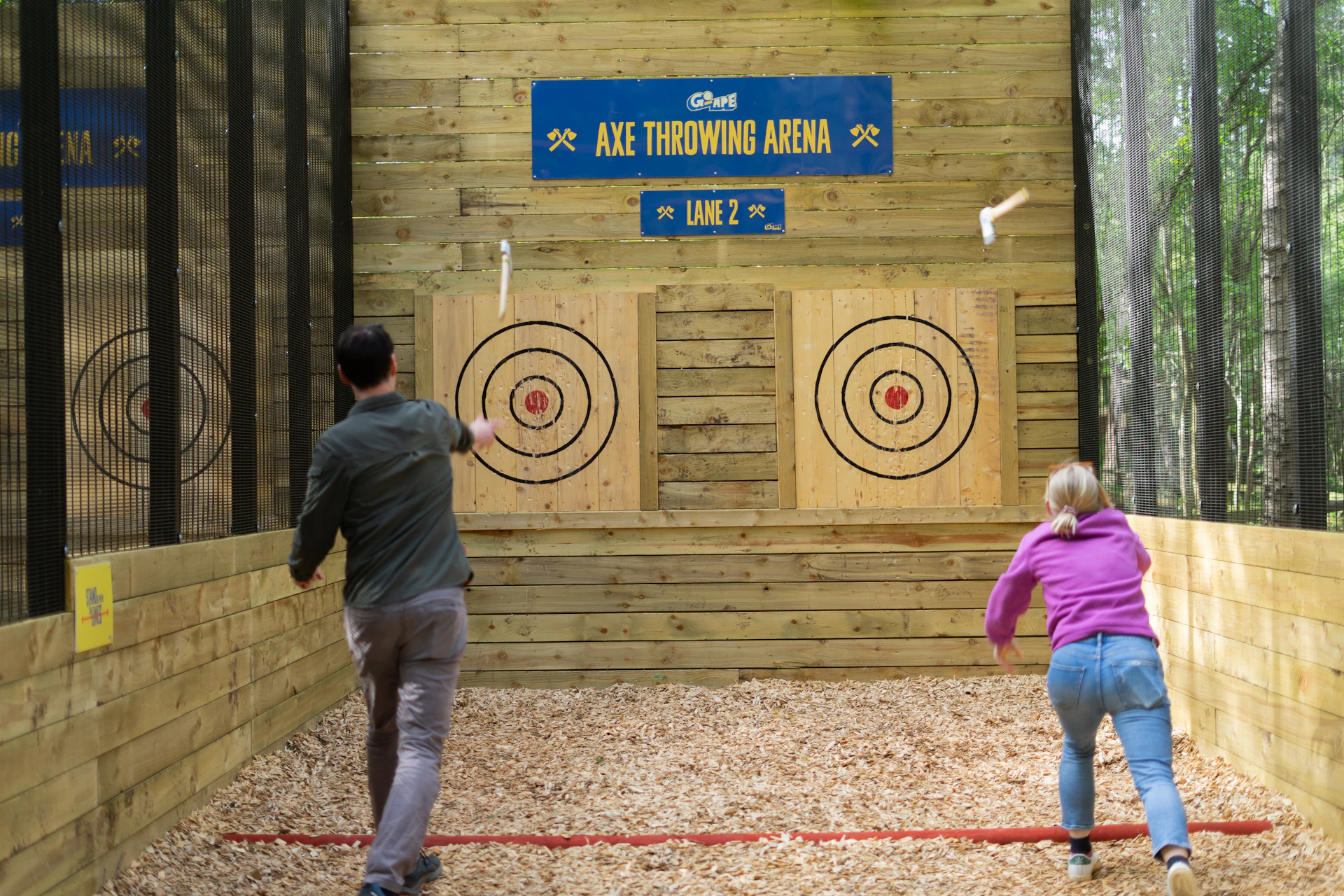 Two people throwing axes at two targets.