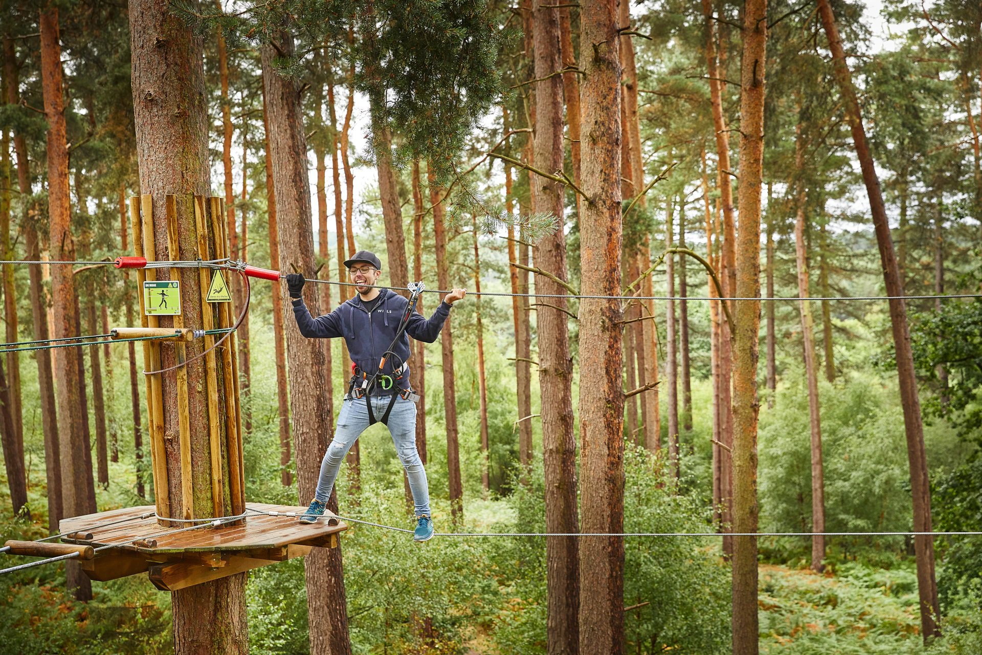 Person on a thin wire crossing on a high ropes course.