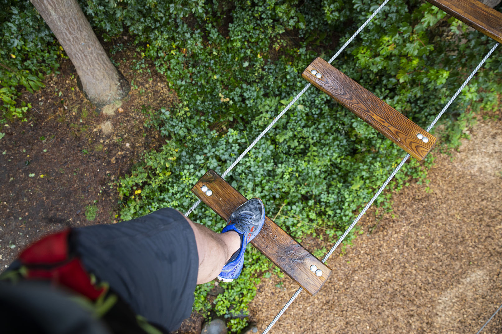 Focus on a person's trainers as they step across a high ropes crossing.