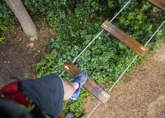 Focus on a person's trainers as they step across a high ropes crossing.