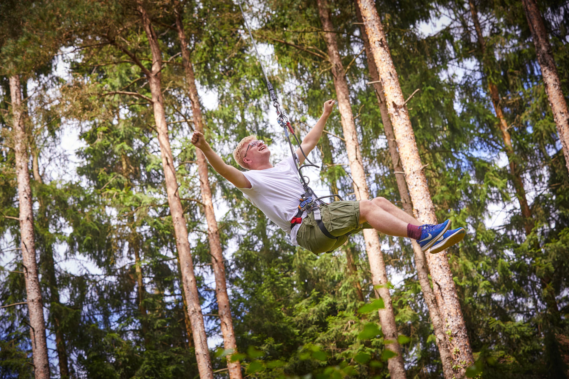 Person on a zipline near trees.
