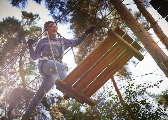 Person above crossing a high ropes obstacle.
