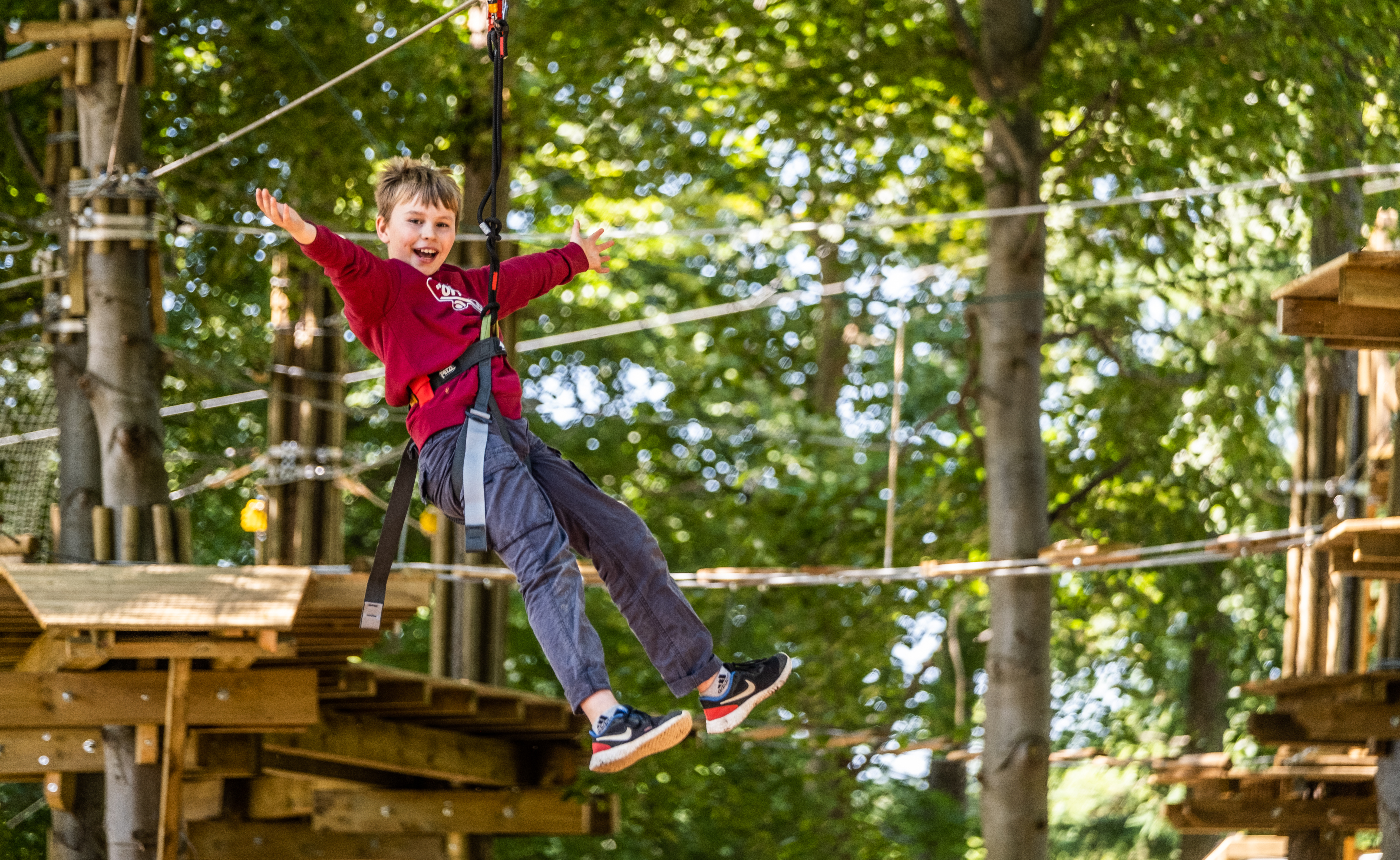 Young person on a zip wire with their arms wide.