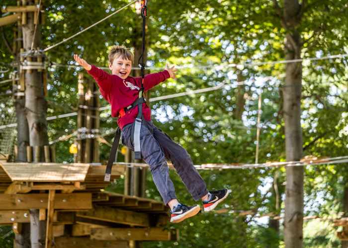 Young person on a zip wire with their arms wide.