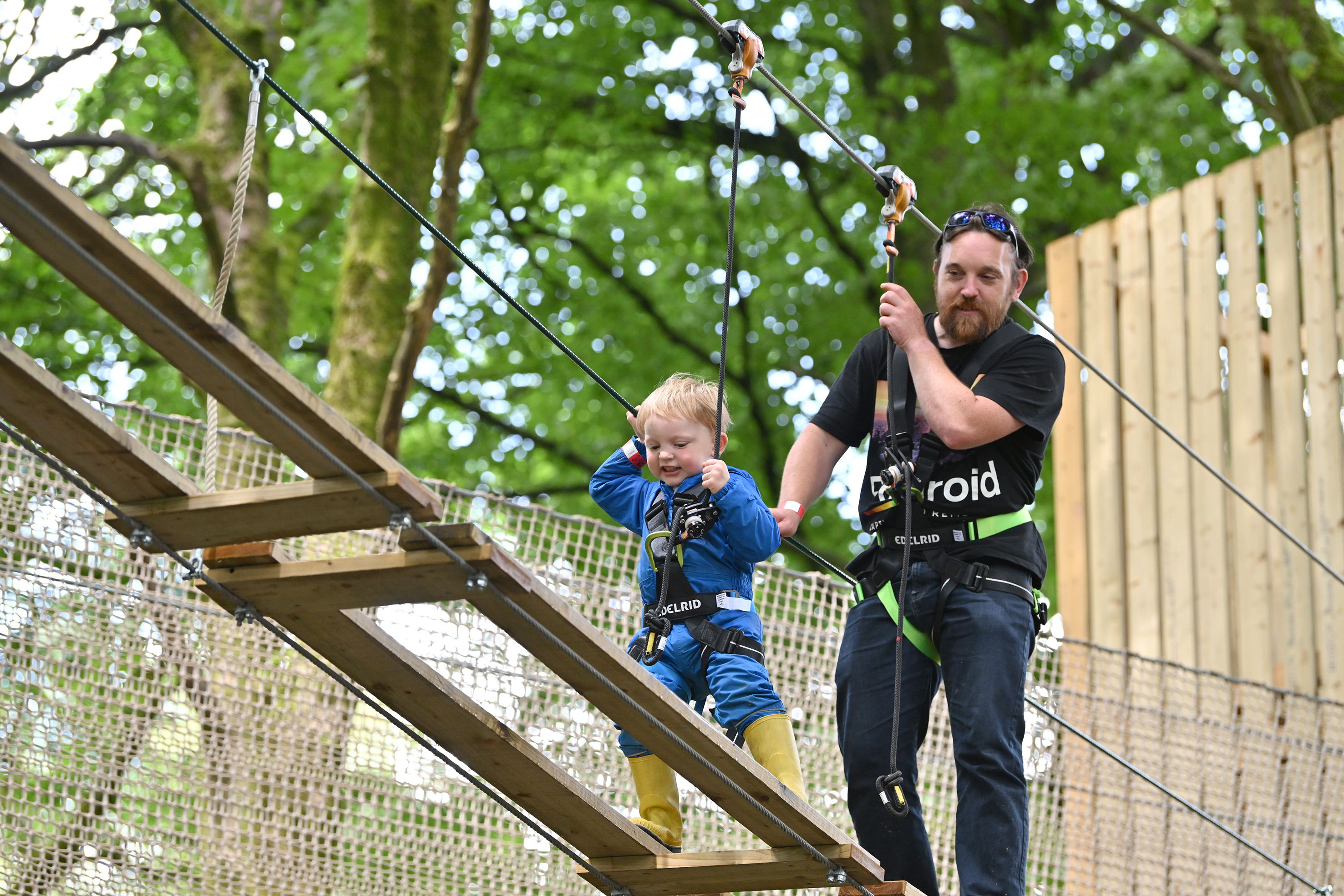 Child on a high ropes course while an adult supervises.
