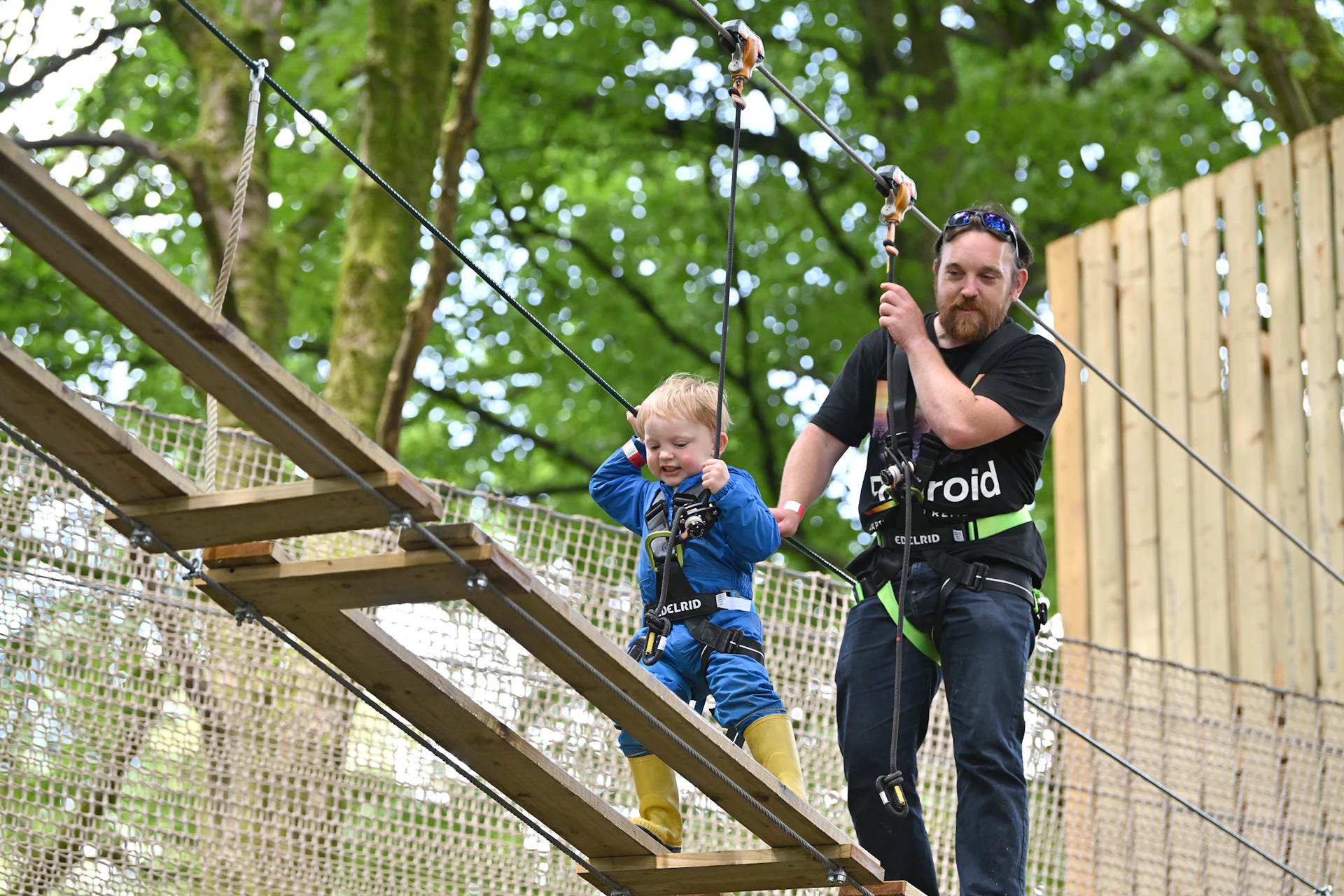 Child on a high ropes course while an adult supervises.