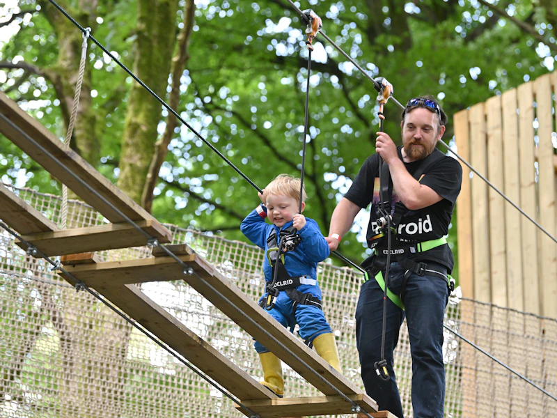 Child on a high ropes course while an adult supervises.