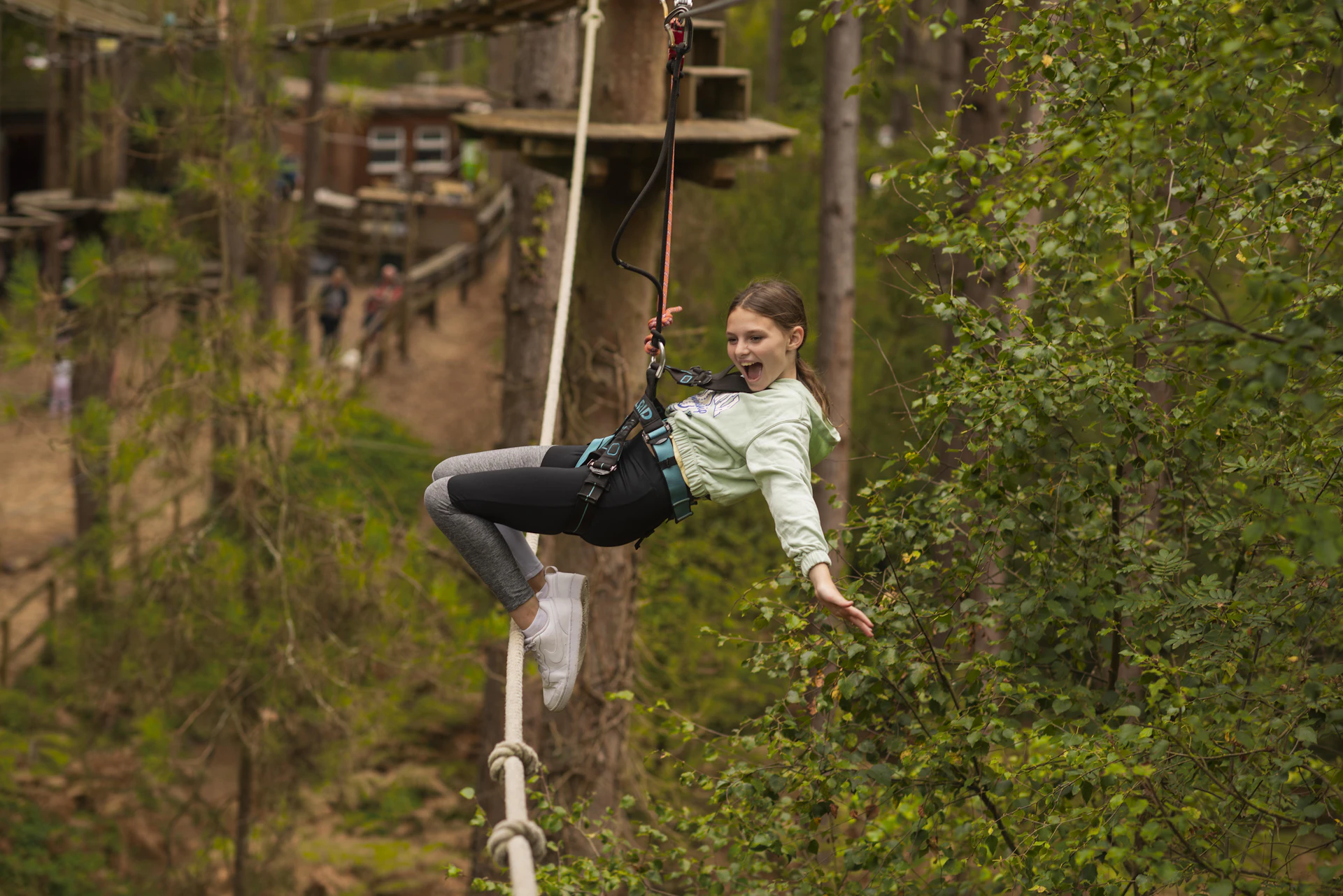 A girl enjoyes a thrilling zip across a Go Ape crossing in the forest