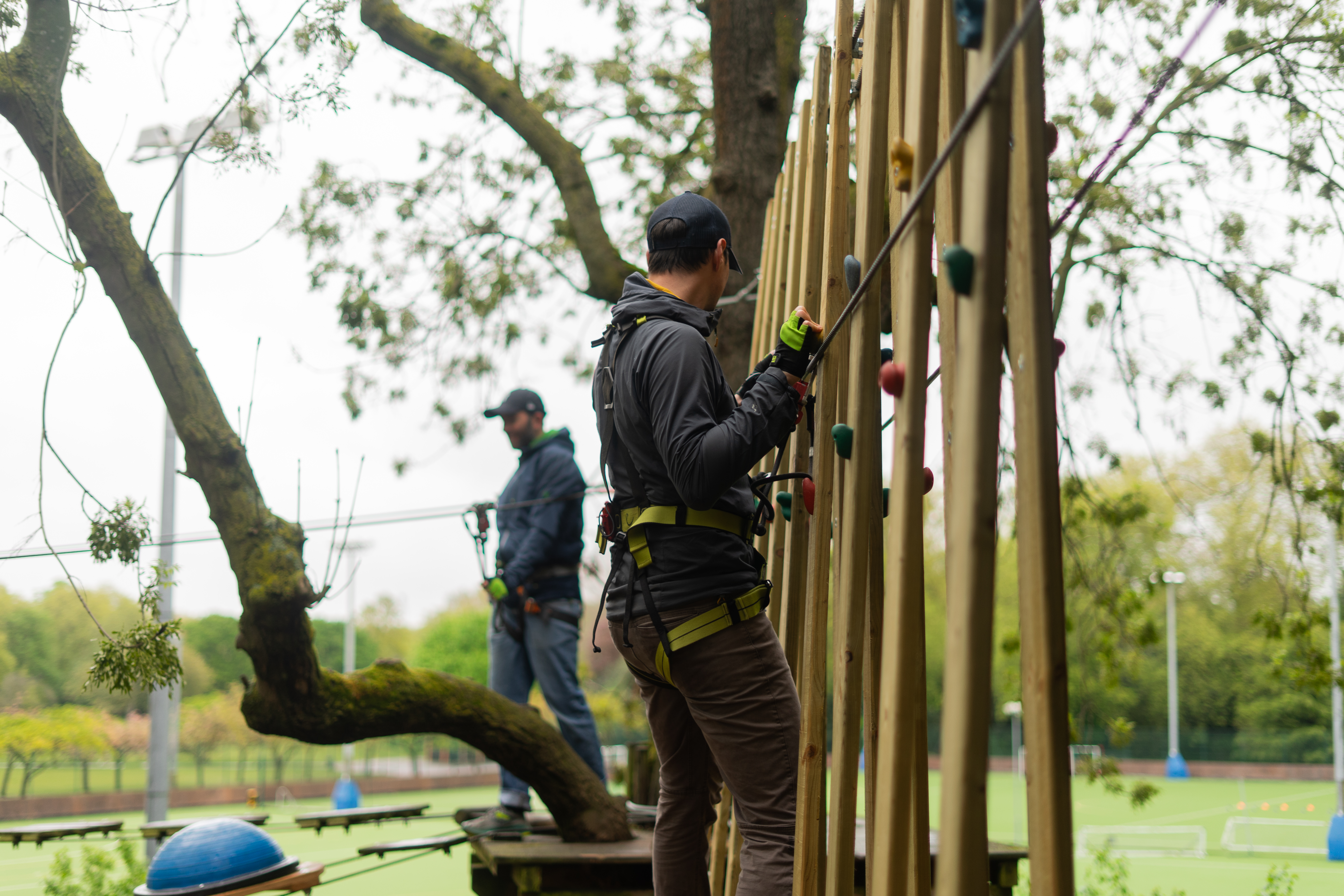 Person crosses a horizontal climbing wall on a high ropes course.