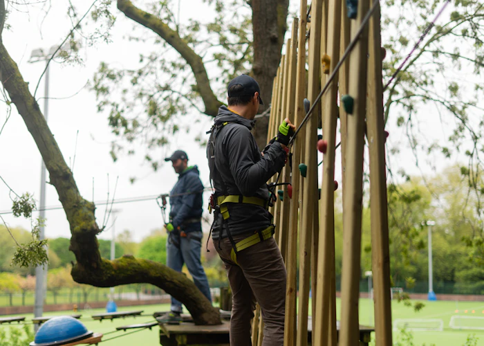 Person crosses a horizontal climbing wall on a high ropes course.