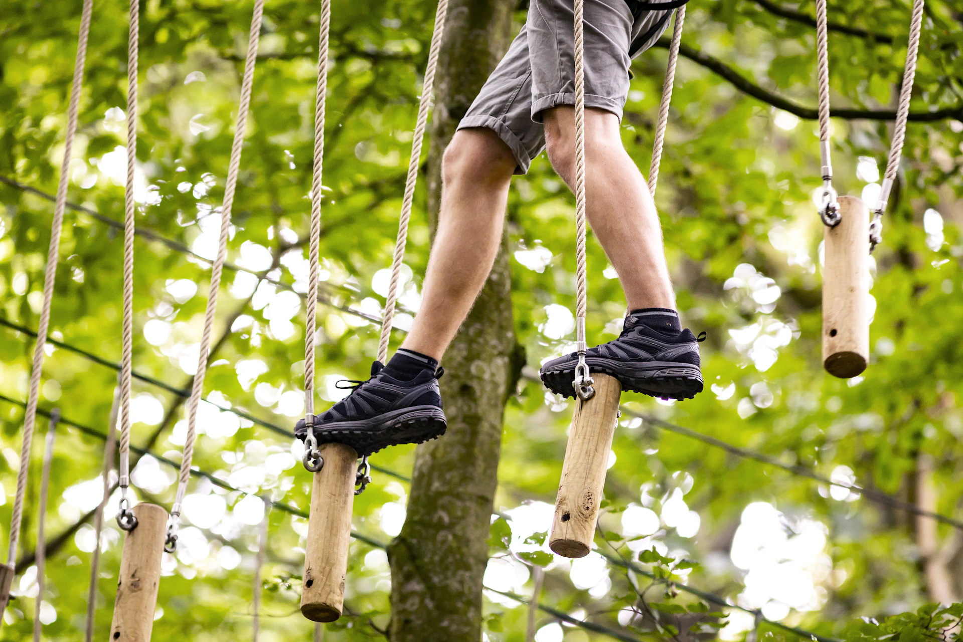 Focus on a person's trainers as they step across a high ropes crossing.