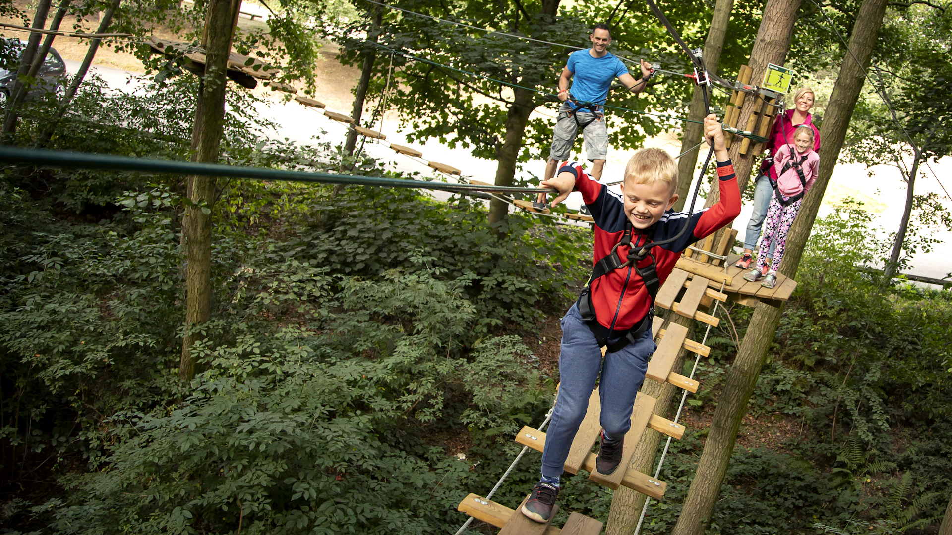 Young people and two adults on a high ropes course.