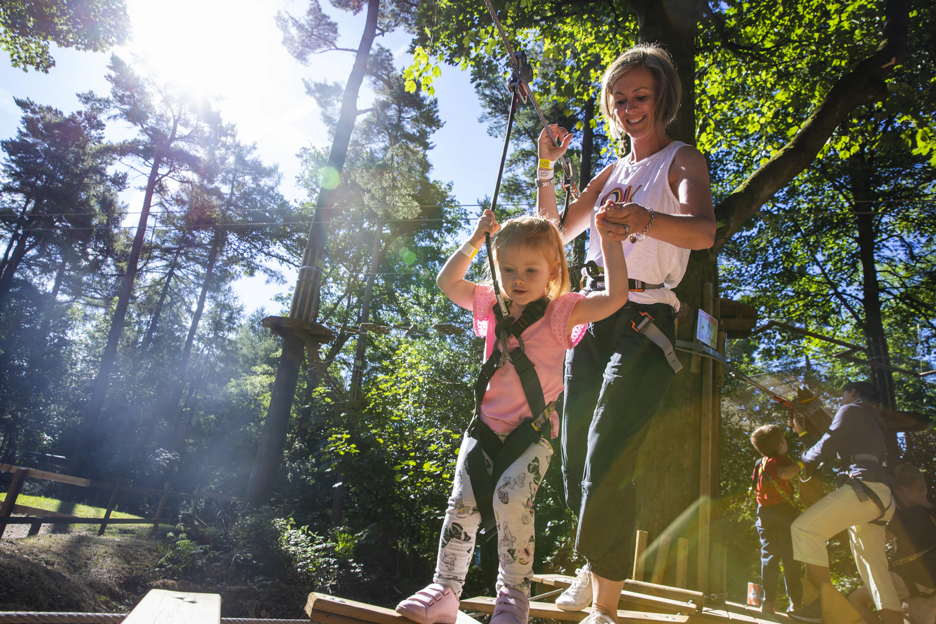 A young girl and her mum hold hands as she negotiates a ropes crossing.