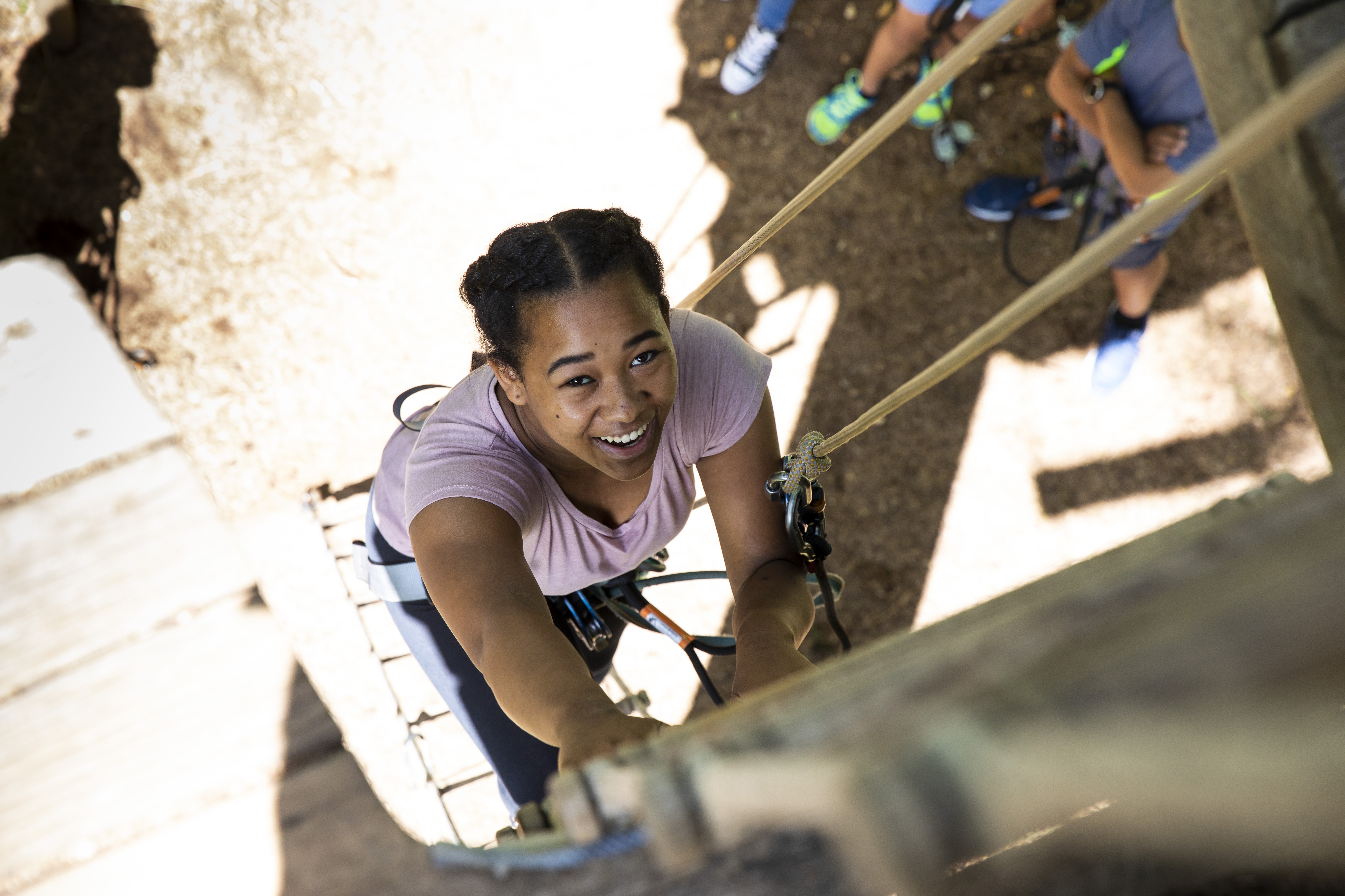 Young person climbs a ladder on a high ropes course.