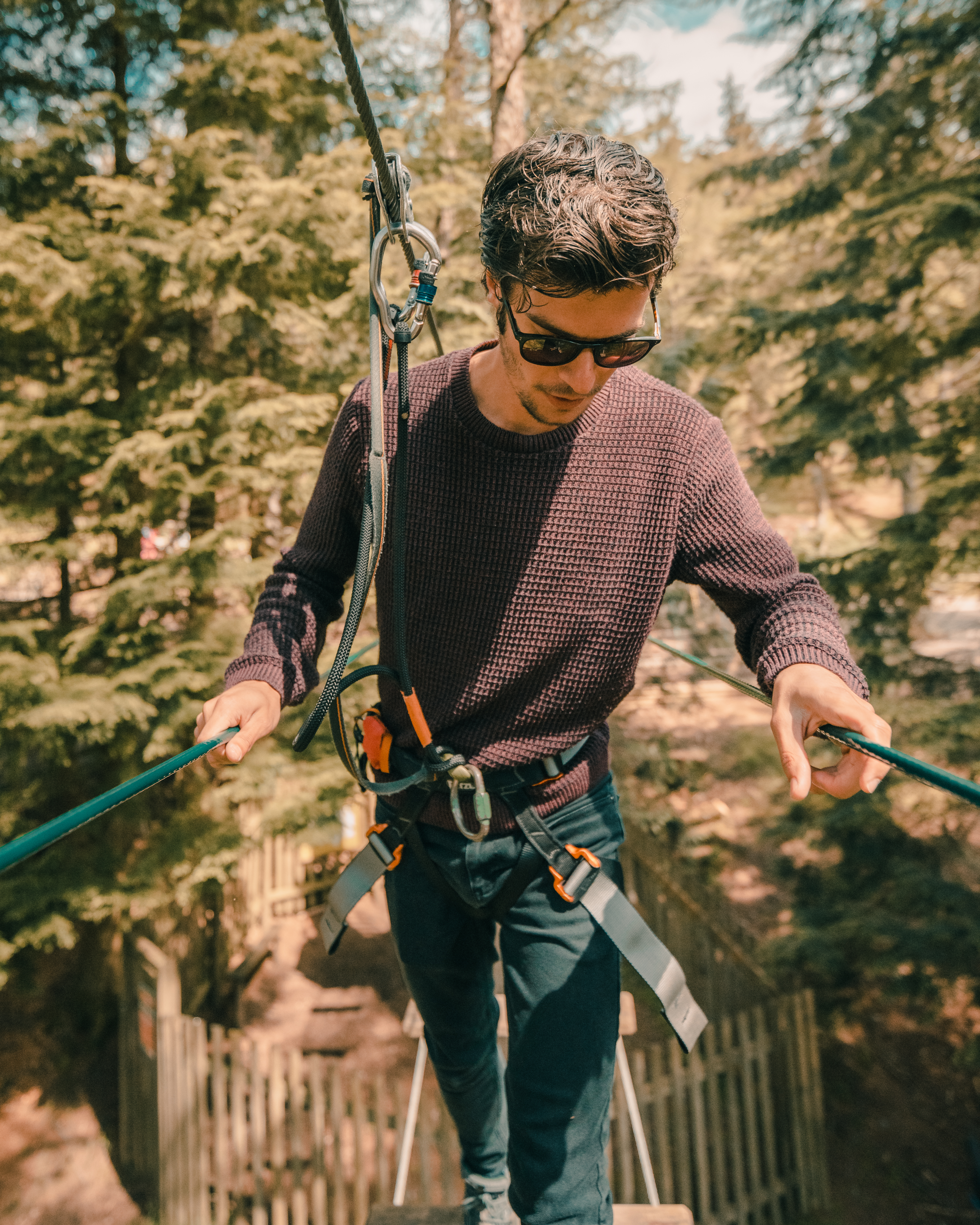 A man concentrates as he makes his way over a high ropes crossing on a sunny day out