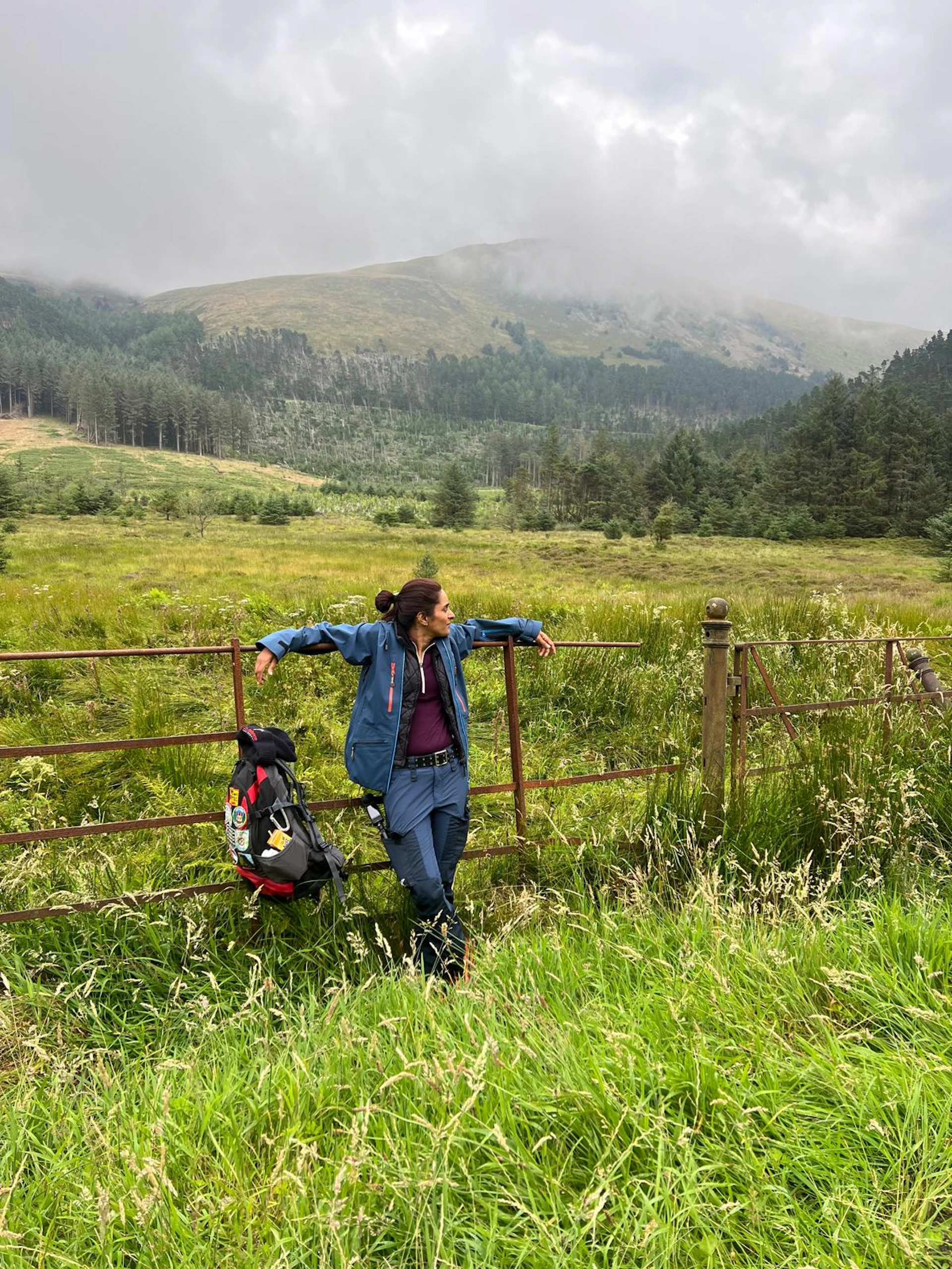 Person standing near a fence with beautiful hills beyond.