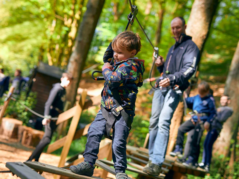 A young boy completes a Go Ape crossing on a fund day out with his dad