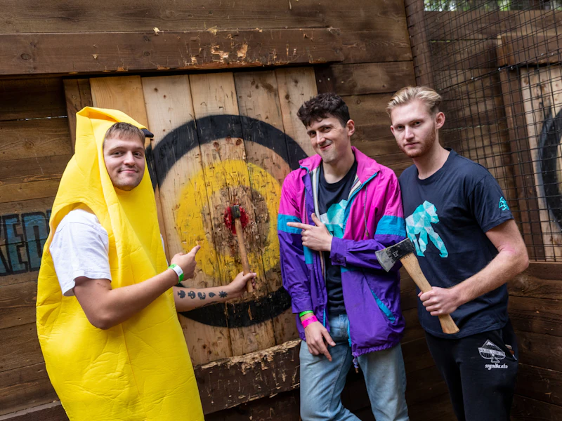 A man wearing a banana suit celebrates with his mates after hitting a bullseye during his Axe Throwing stag party experience