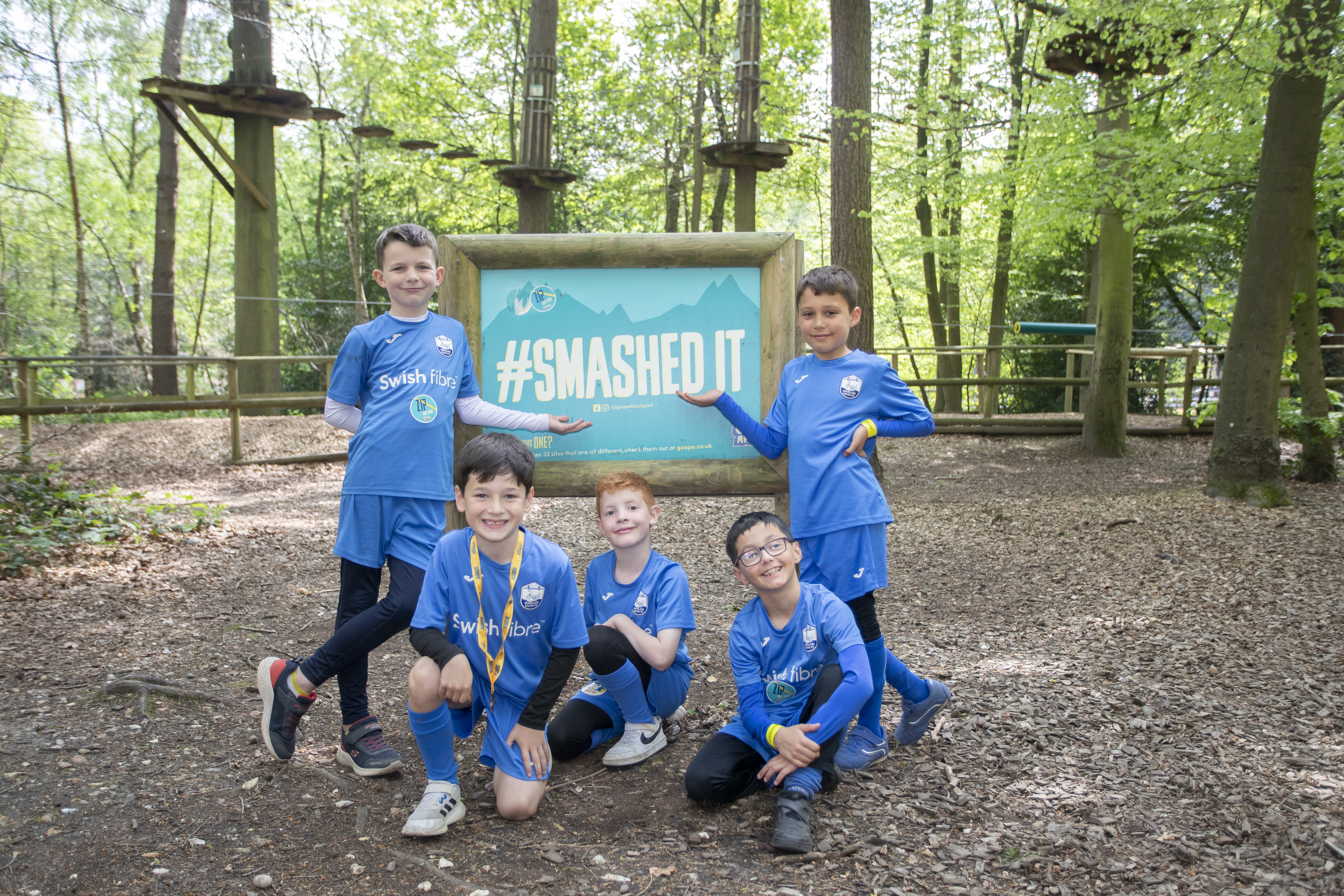 A group of young team mates celebrate their Go Ape visit by the #SmashedIt sign