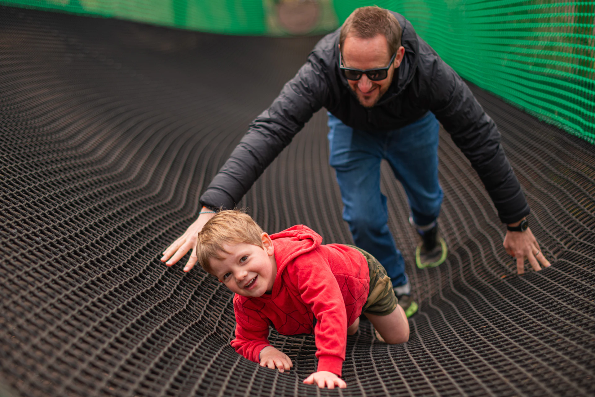 A boy and his dad climb a net ramp on a  Go Ape Nets Adventure