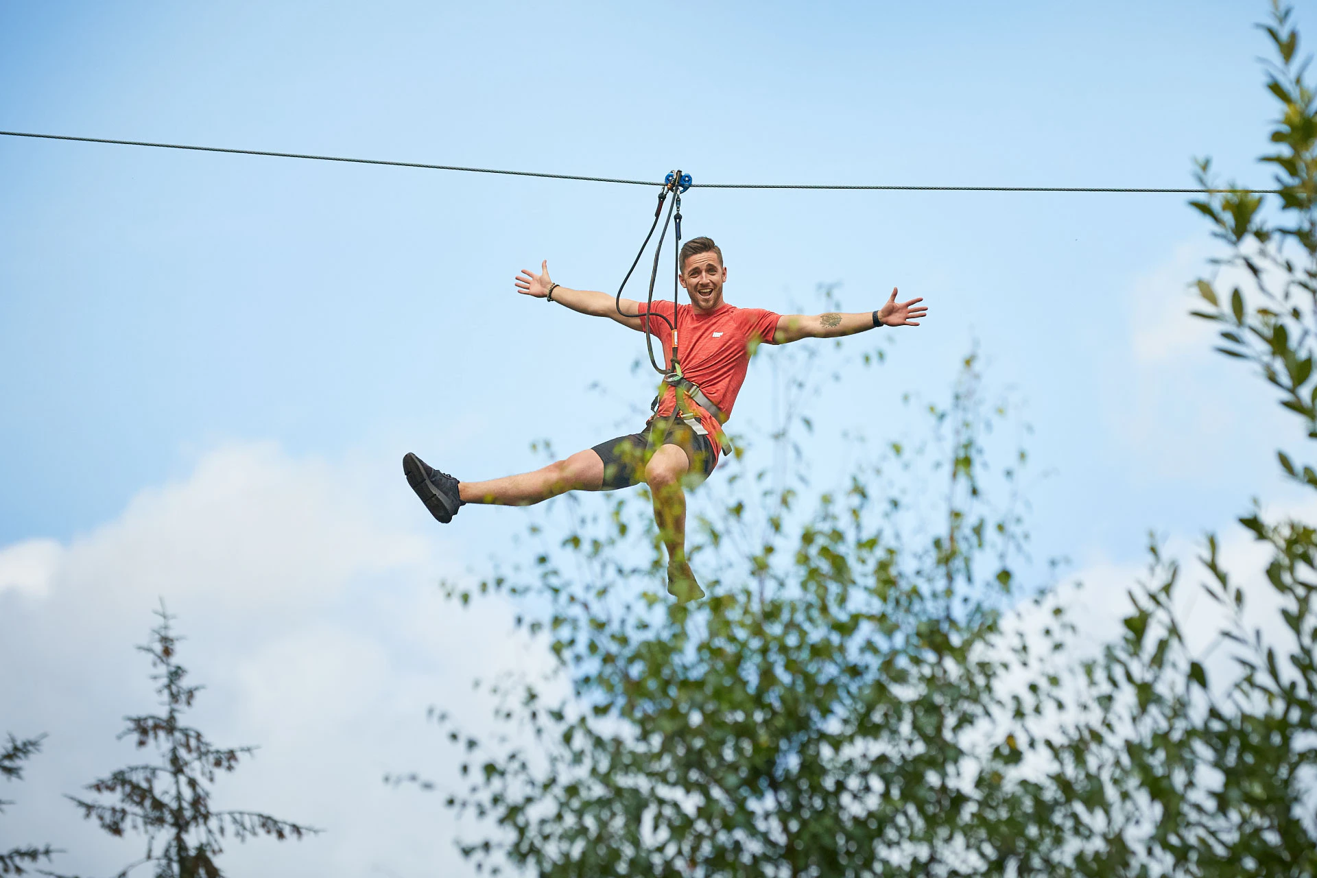 A man rides a zip wire above the forest on a sunny day out
