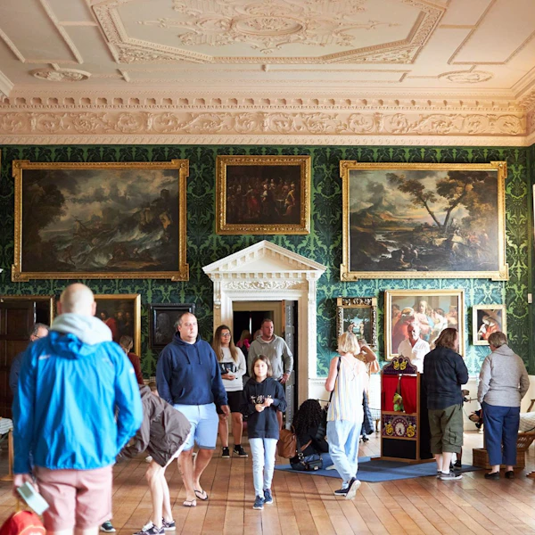 Fine art hangs in a historic room full of visitors to Temple Newsam House
