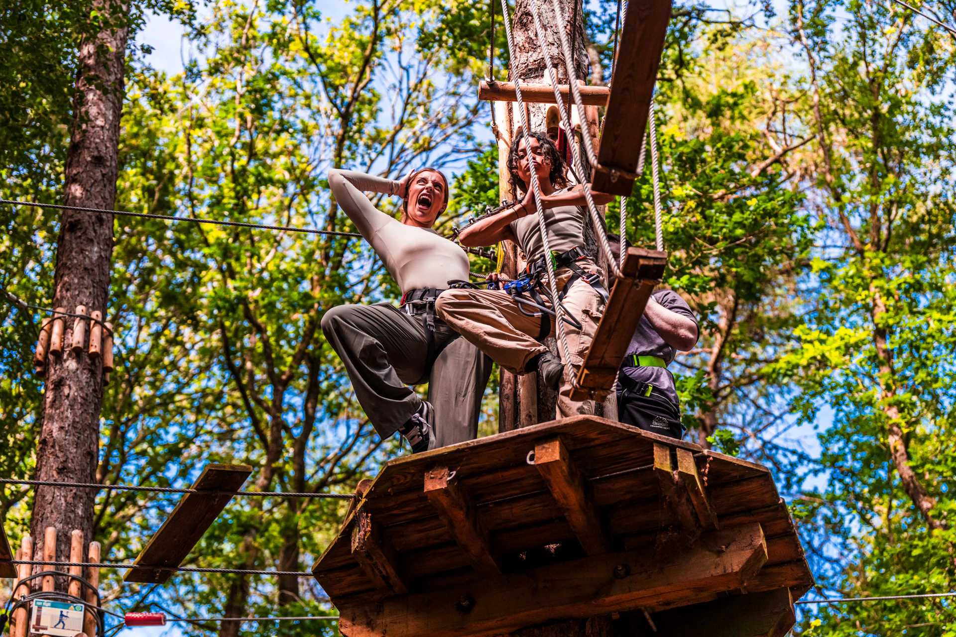 Two women pose on a platform high into the canopy on a Go Ape adventure day out