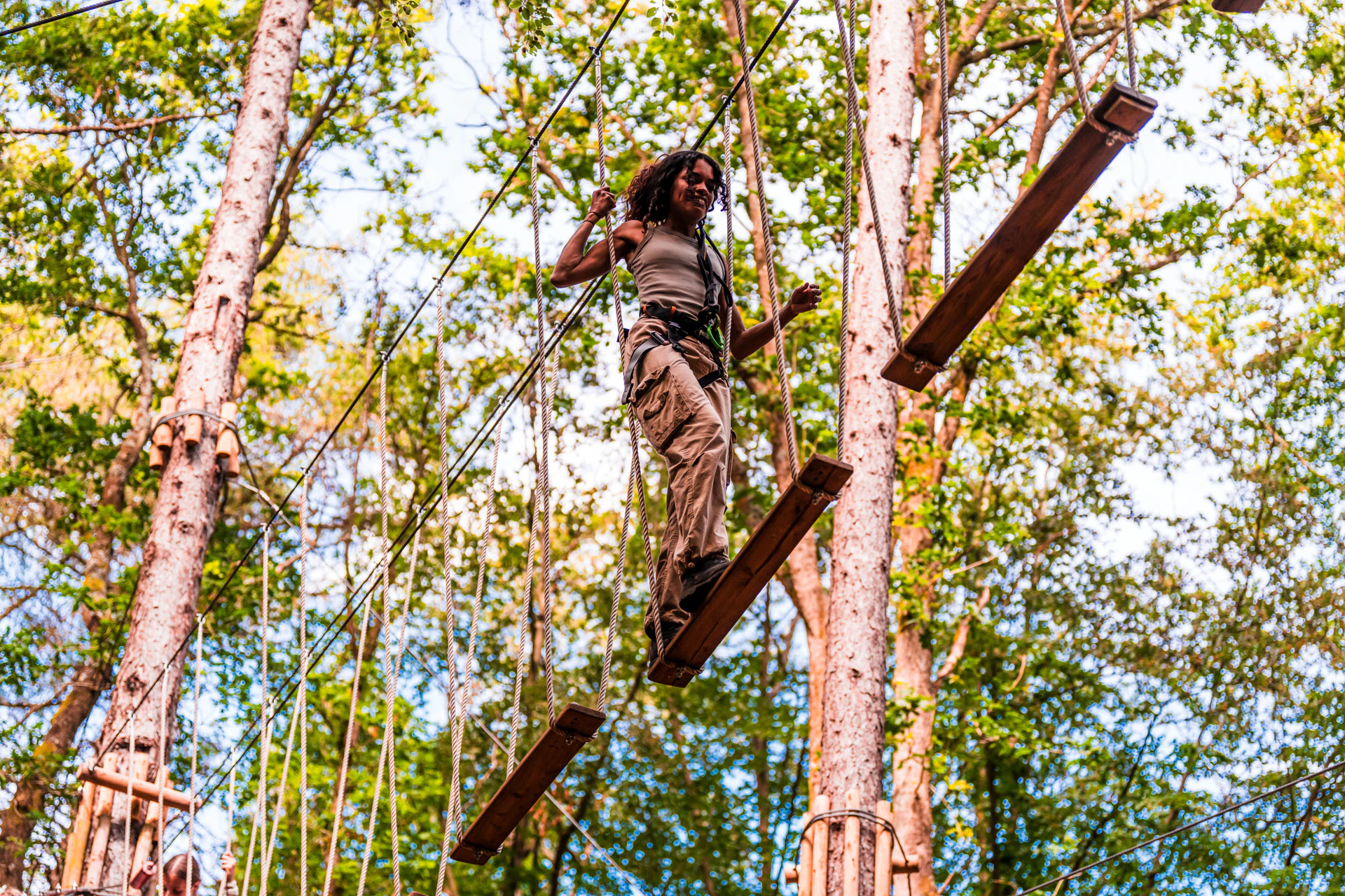 A woman nagivates a wobbly treetop crossing on a day out at Go Ape