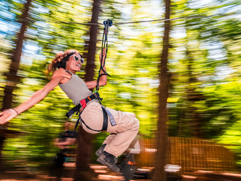 Woman on zip wire in summer A woman holds out her arm as she rides a zip wir eon a sunny day