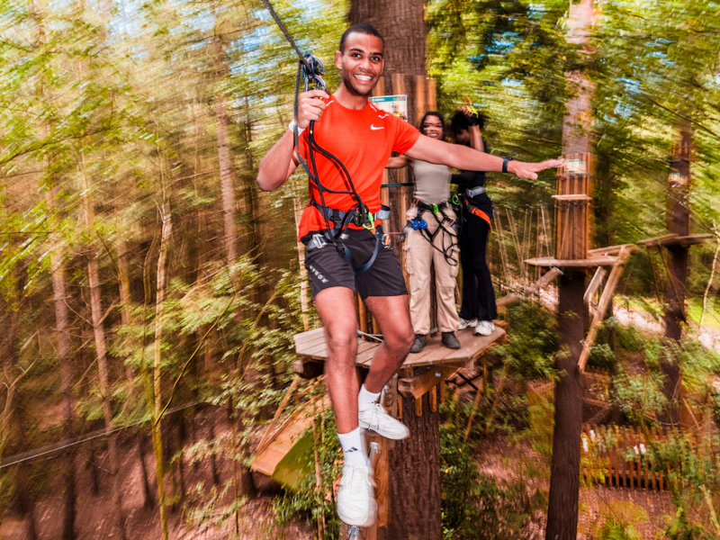 Man balances on crossing A man balances on a high ropes crossing in the forest