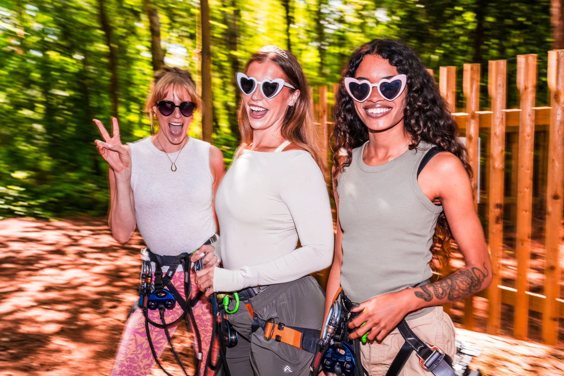 A group of women wearing sunglasses and harnesses pose for a photo on a sunny day for their Go Ape adventure