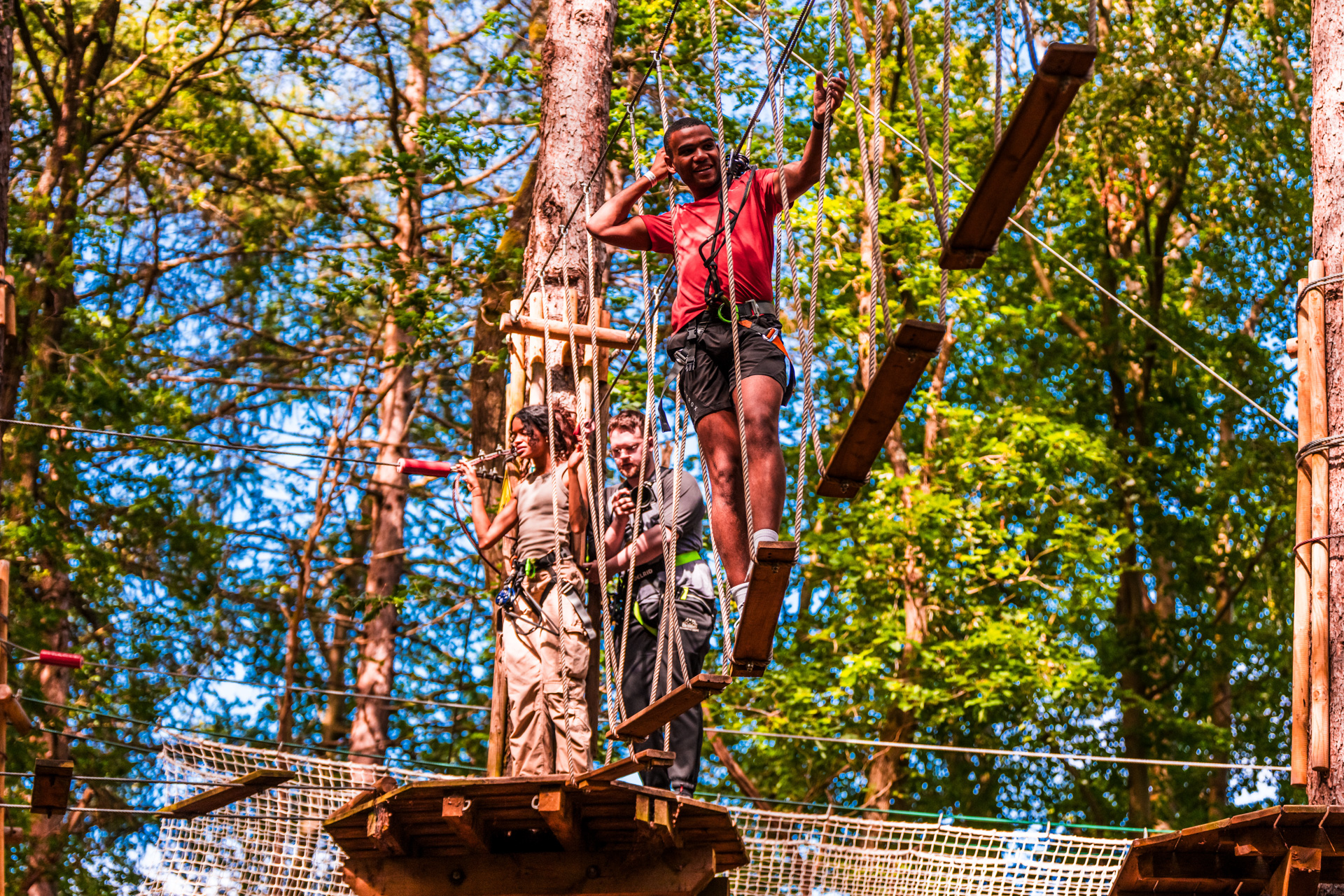 A man navigates a tricky high ropes corssing on a sunny day