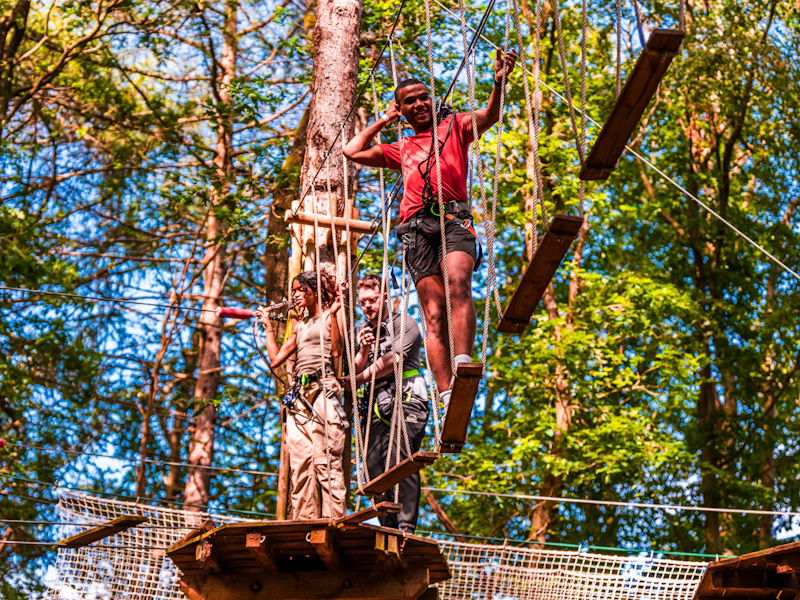 Man on Walk the Plank crossing A man navigates a tricky high ropes corssing on a sunny day