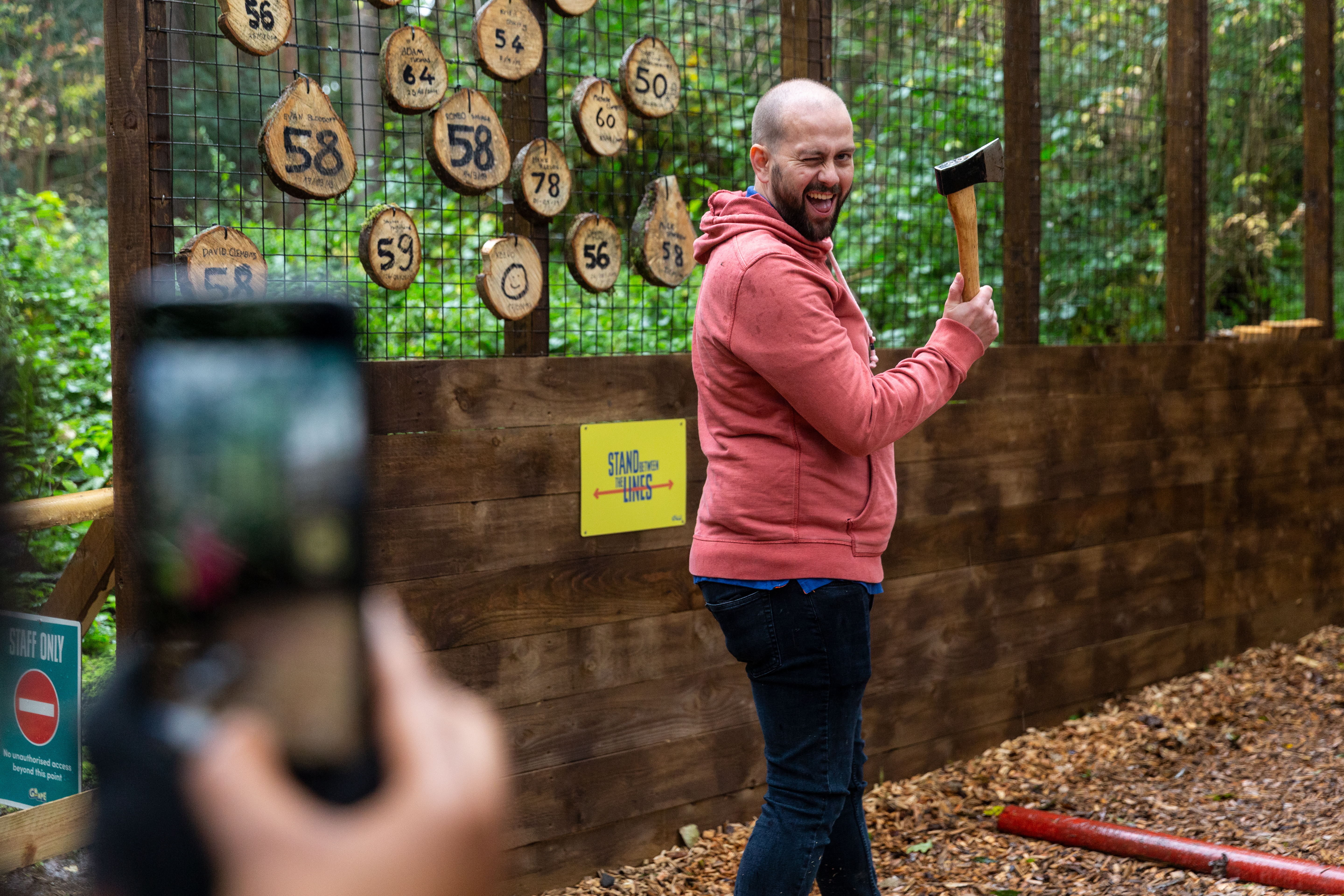 A man winks at the camera as he prepares to throw an axe