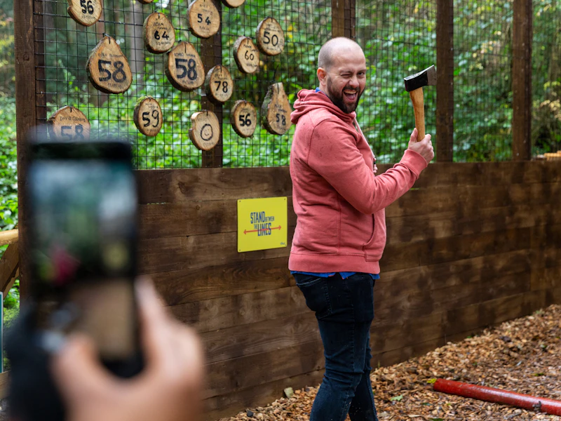Axe Throwing wink A man winks at the camera as he prepares to throw an axe