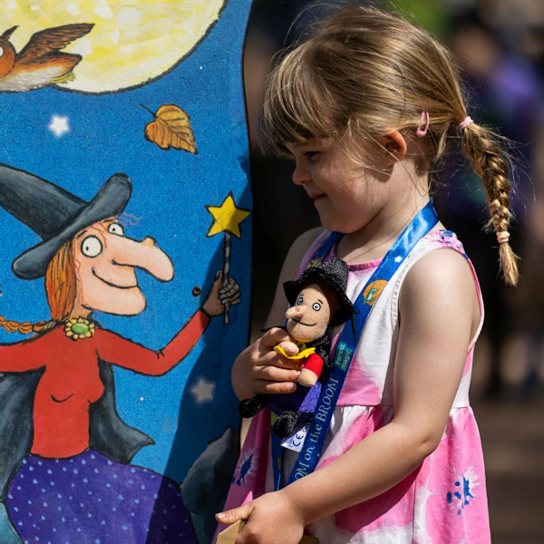 A small girl by a Room on the Broom trail sign