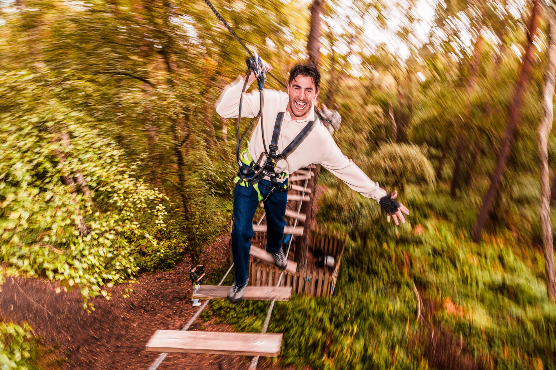 A man smiles as he balances on a high ropes crossing during his day out at Go Ape