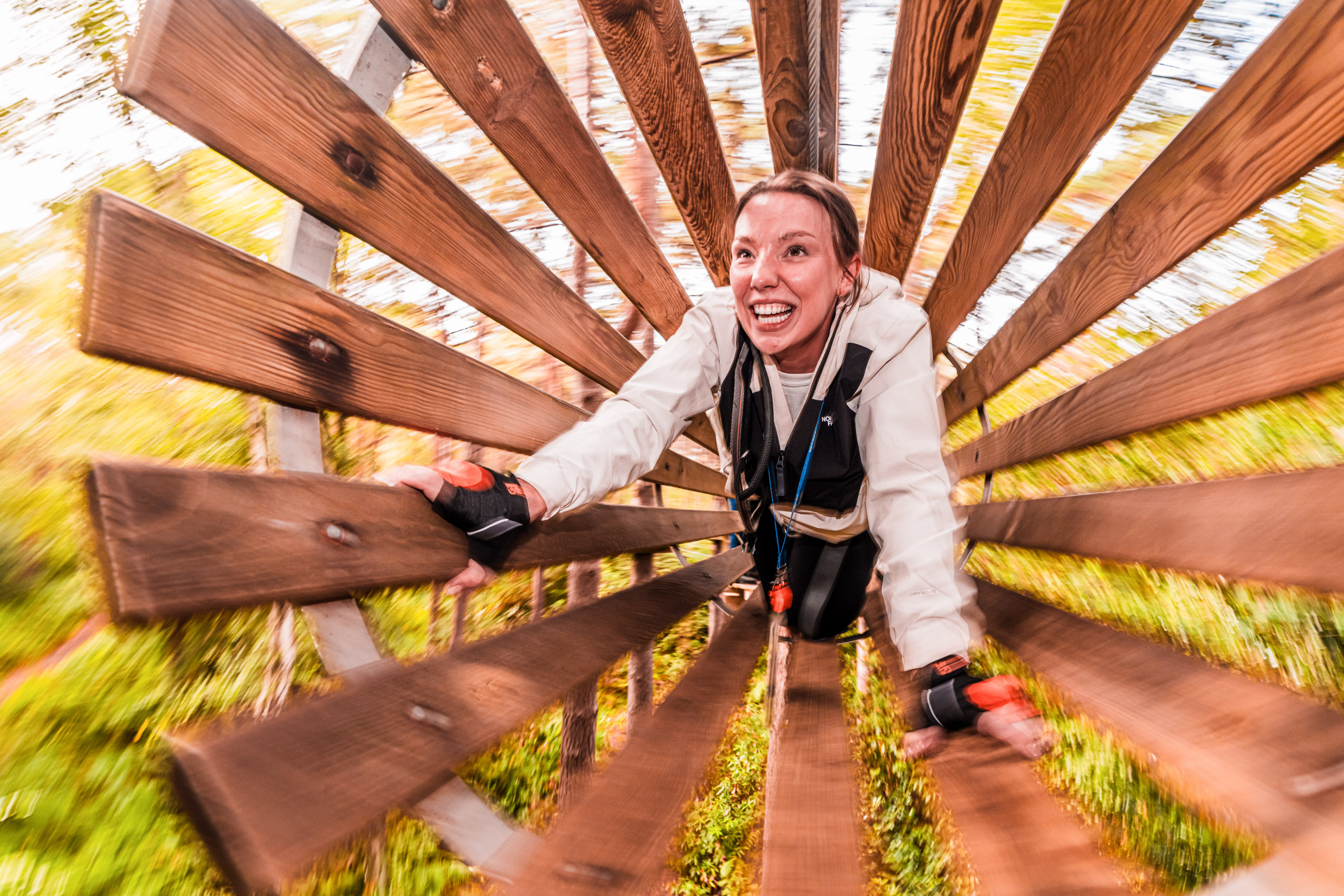 A woman clambers througha wooden tunnel in the treetop on a fund day out for a high ropes adventure