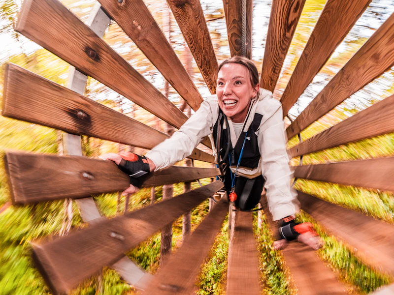 Tunnel Crossing Woman A woman clambers througha wooden tunnel in the treetop on a fund day out for a high ropes adventure