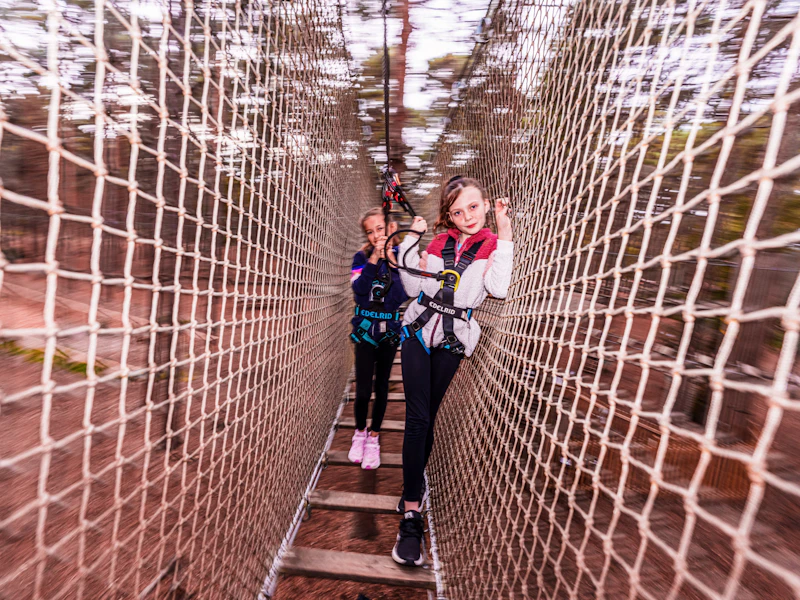 Colongalook Crossing Two girls pose for a photo mid-way through a high ropes crossing at Go Ape