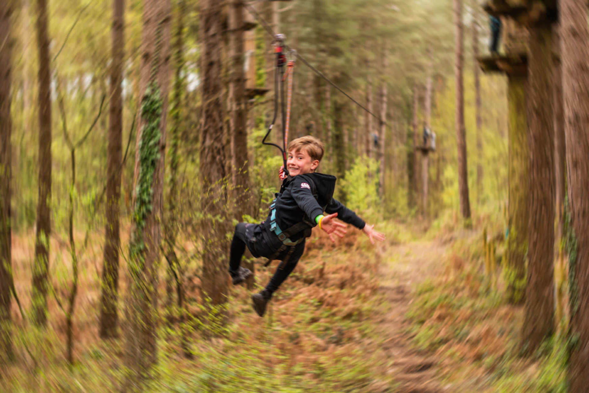 A boy looks over his shoulder and smiles as he rides a zip wire on a fin day out